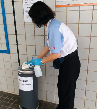 Ms. Ng cleaning the bins for disposal of used face masks.