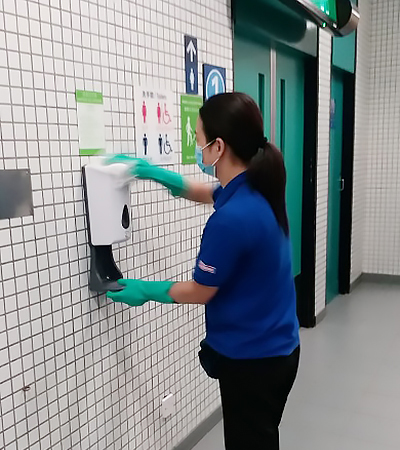 Ms. Cheung refilling a hand sanitizer dispenser.